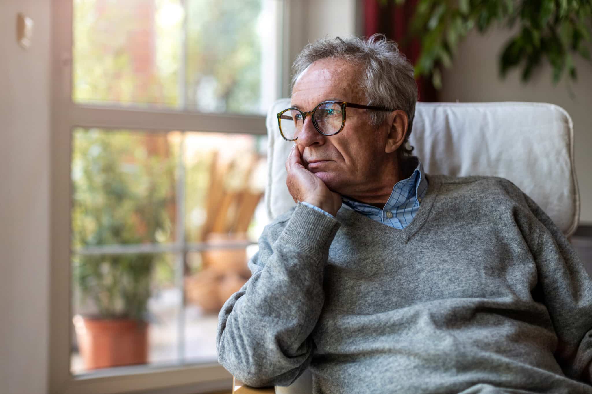 Older man looking out the window of his home.