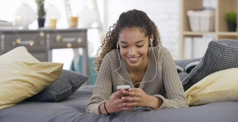 teen girl browses her phone with earbuds