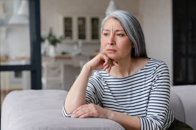 Woman looking despondent sitting at her kitchen counter.