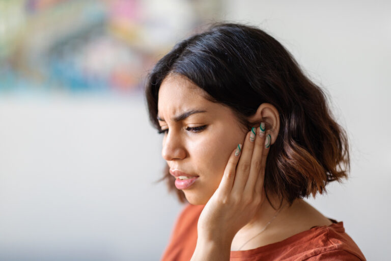 Woman with tinnitus holds ear to hand